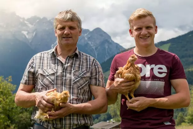 Vater und Sohn halten zwei Wildhendl in der Hand und lachen in die Kamera